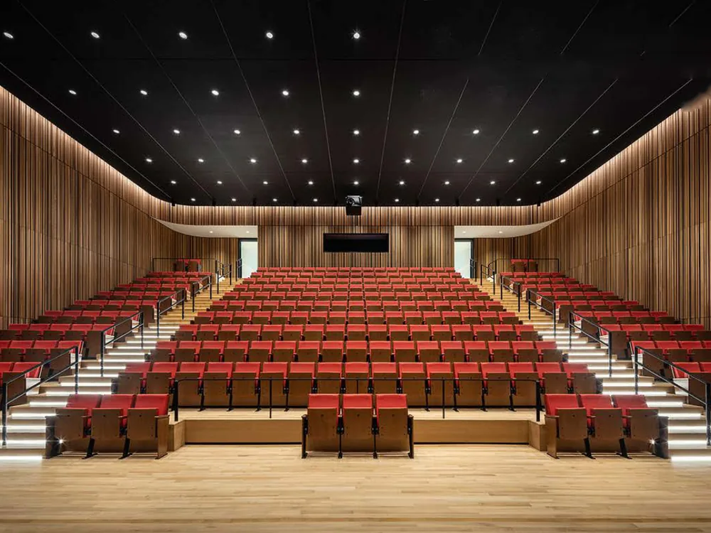 300-seat multipurpose hall with timber slat walls and raked seating