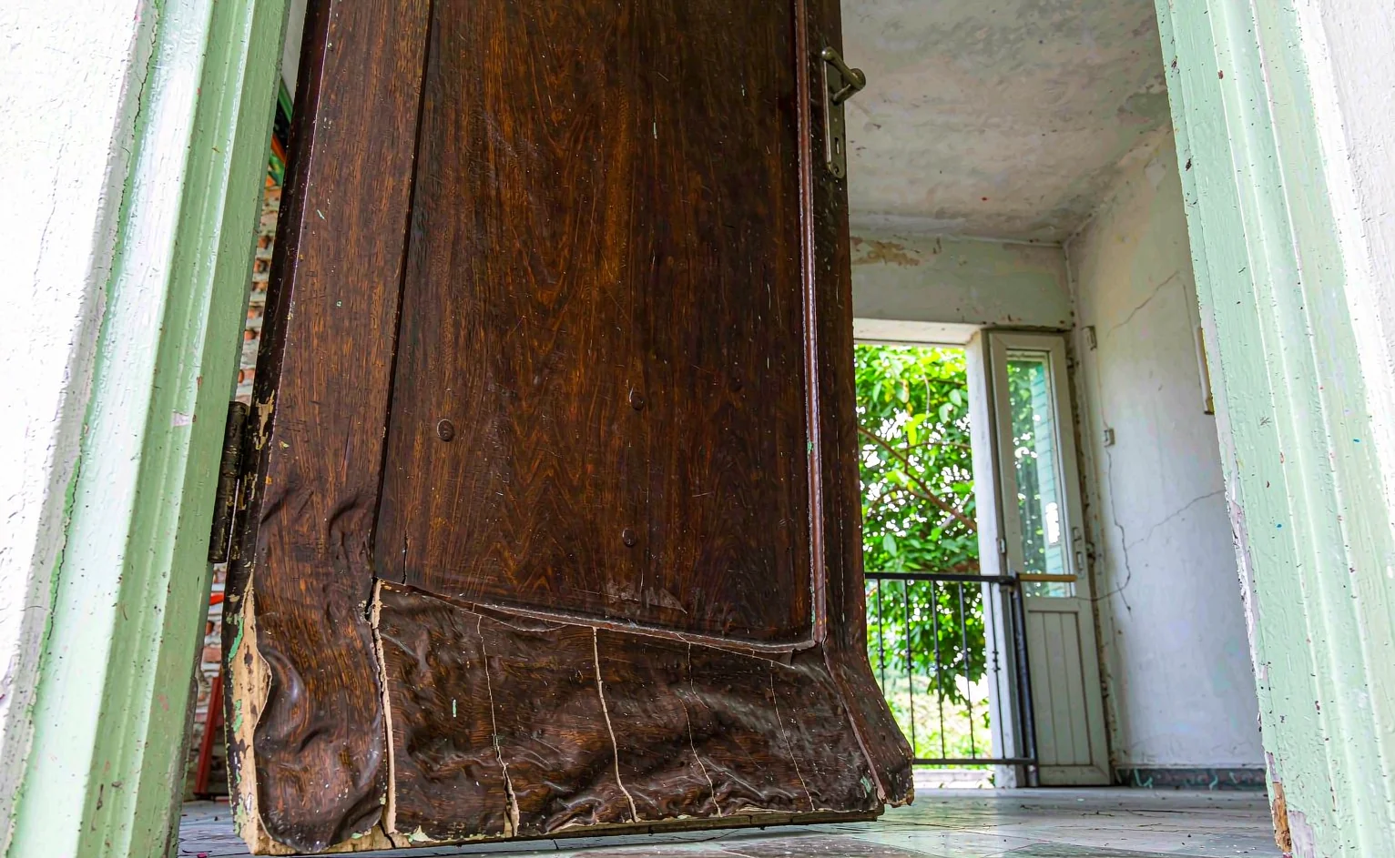 Swollen warped solid wood door scraping the frame in a humid tropical interior