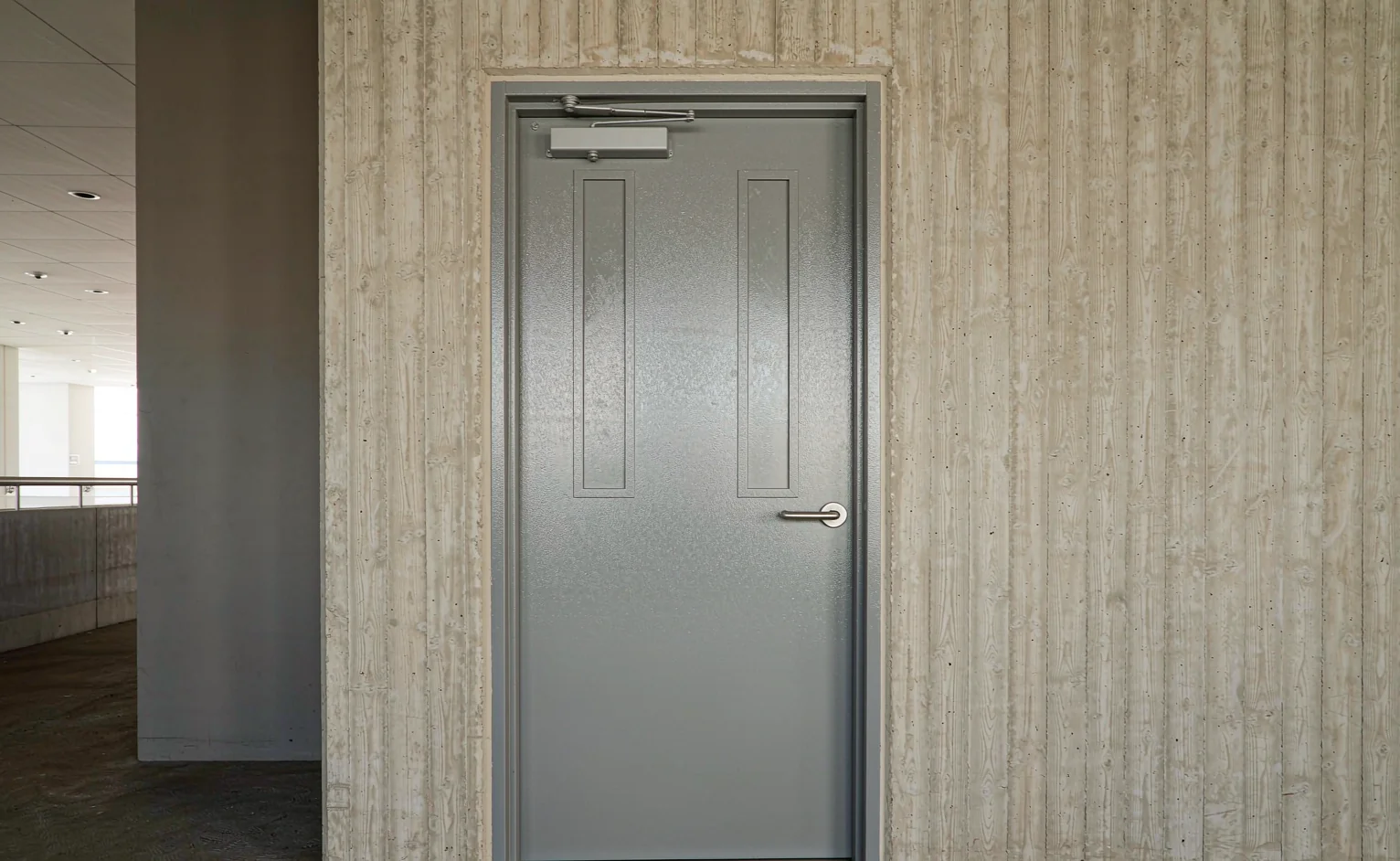 Galvanized steel fire-rated door with overhead closer in a high-rise apartment lift lobby