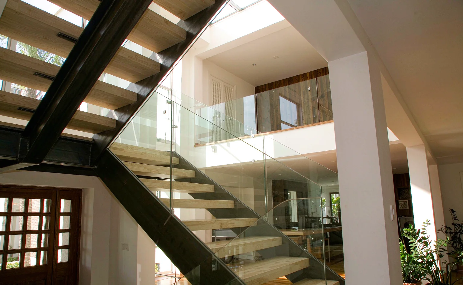 Steel stringer staircase with timber treads and glass balustrade in a bright East African villa foyer