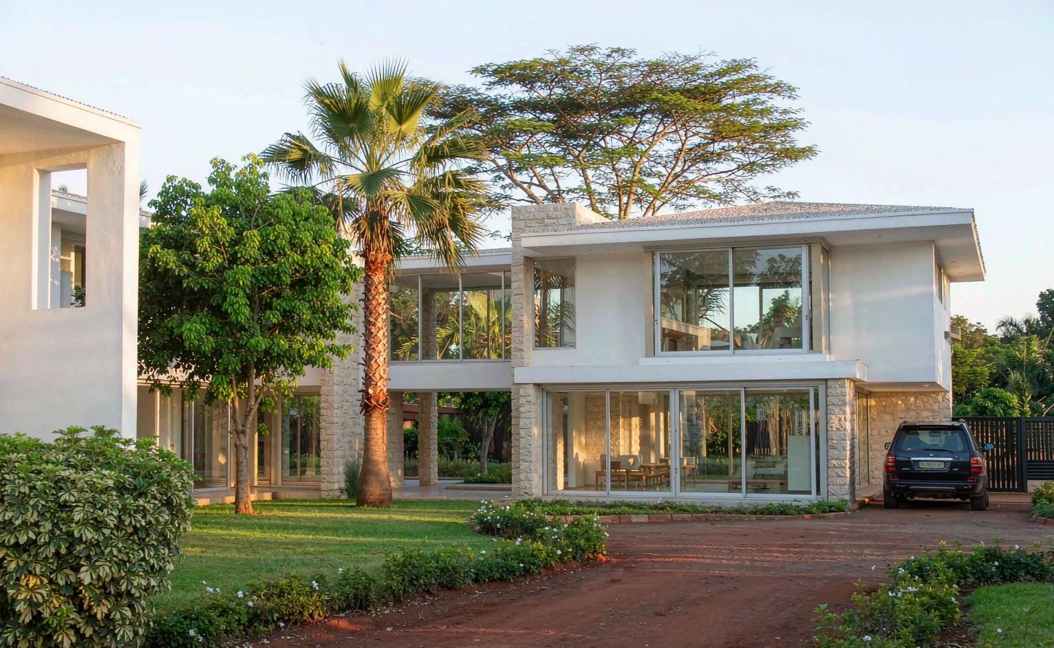 Modern two-storey villa with stone cladding and aluminium glazing on a red-soil plot in Nairobi, Kenya