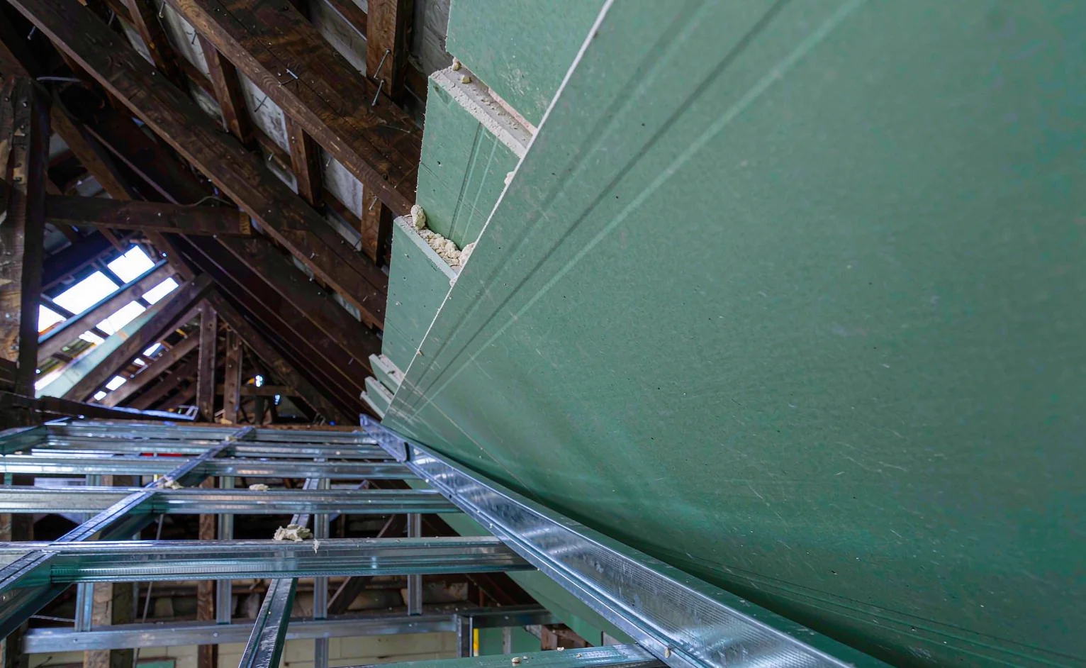Green-core moisture-resistant gypsum plasterboard fixed to galvanised steel furring channels during ceiling installation