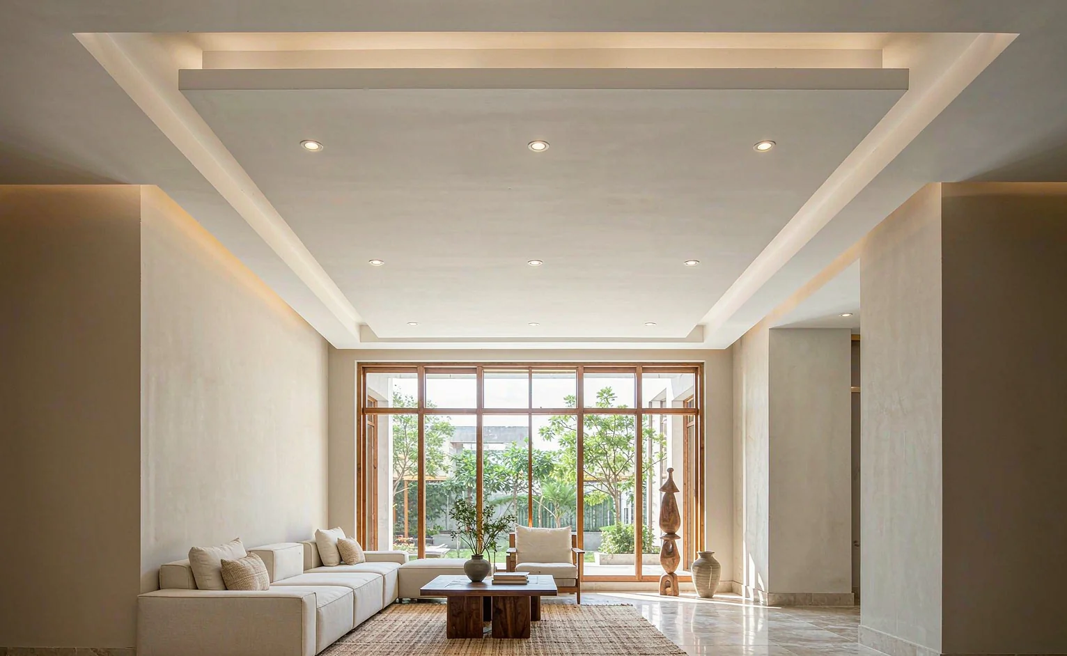 Bright living room with a suspended gypsum ceiling, recessed downlights and a dropped perimeter bulkhead in a hot-climate home