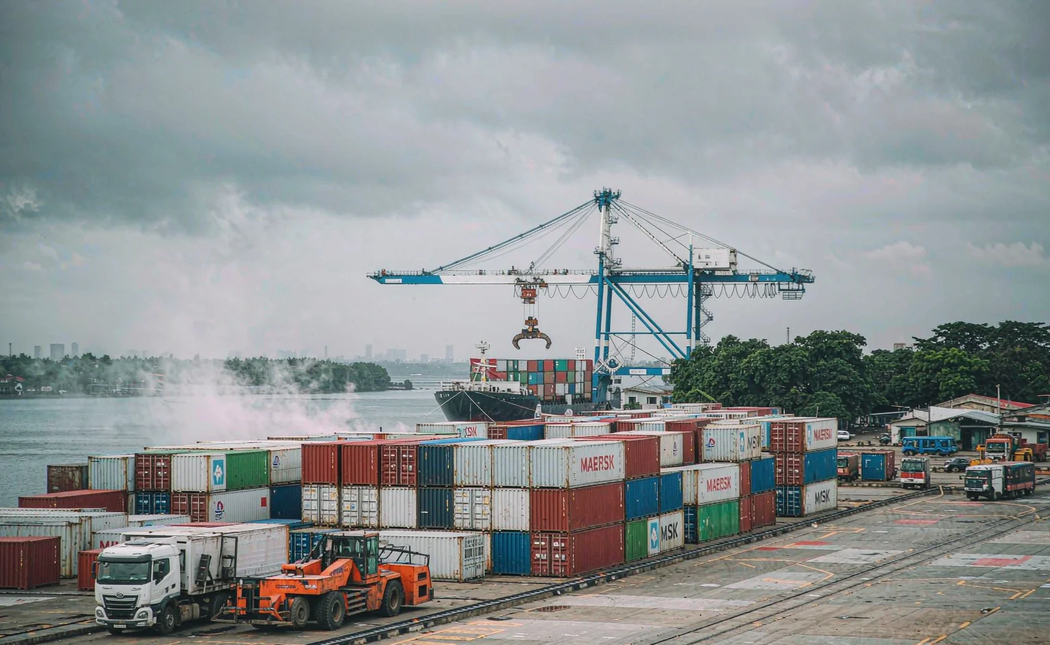 Stacked shipping containers and a gantry crane loading a vessel at a West African container port terminal