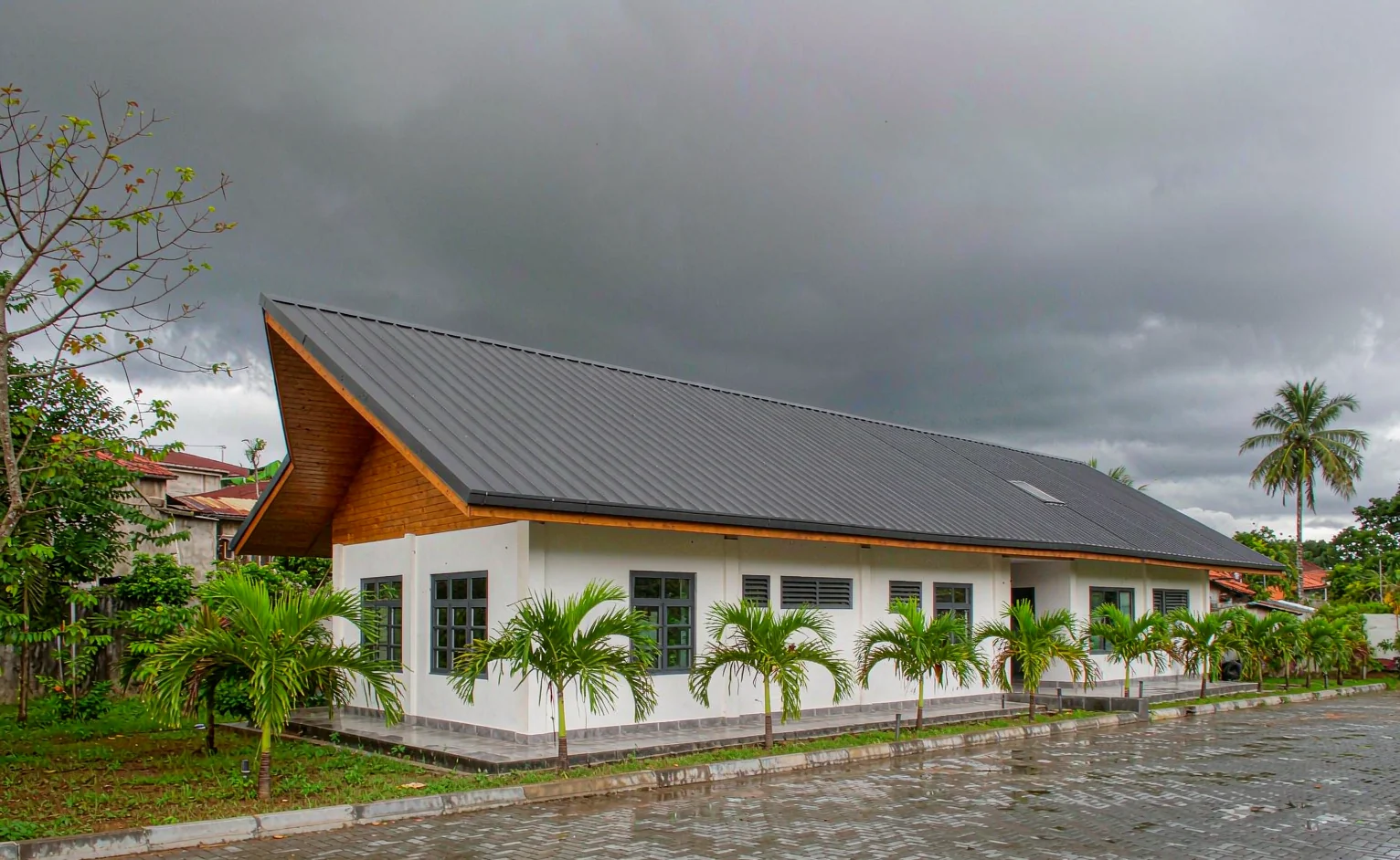 House with a steep pitched metal sheet roof and wide overhanging eaves after heavy tropical rain on the West African coast