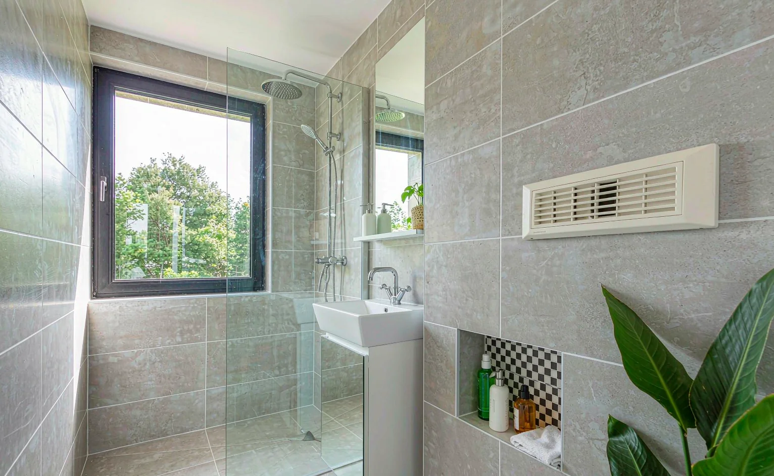 Modern bathroom with large format porcelain wall tiles, wall hung basin and a mechanical extract vent in a humid climate