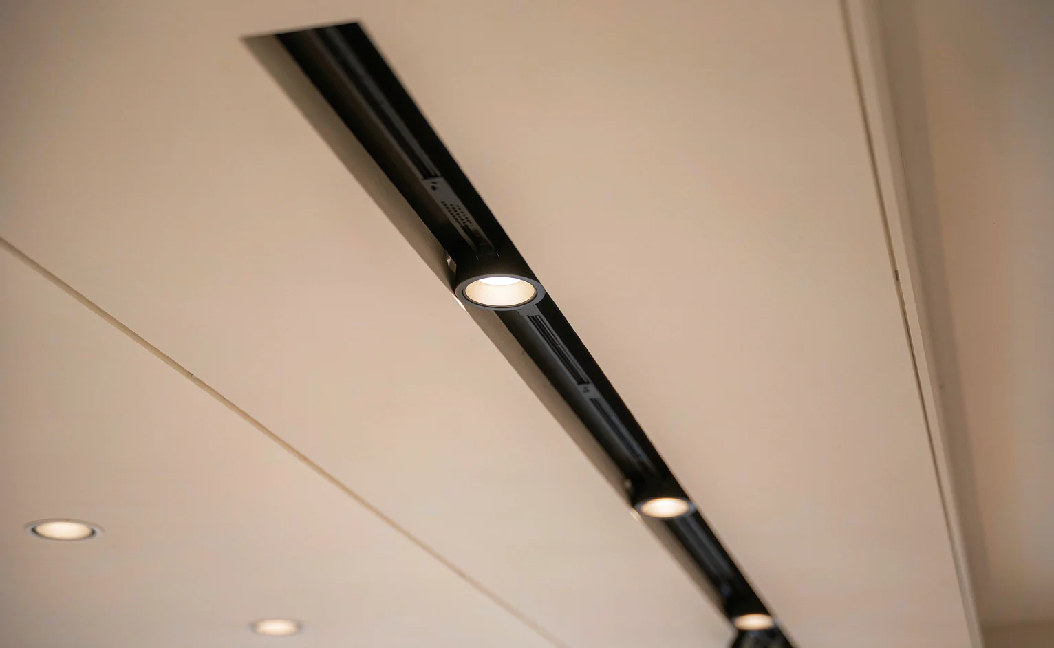 Recessed LED downlights and a recessed magnetic track rail installed in a plaster ceiling in a hot climate interior