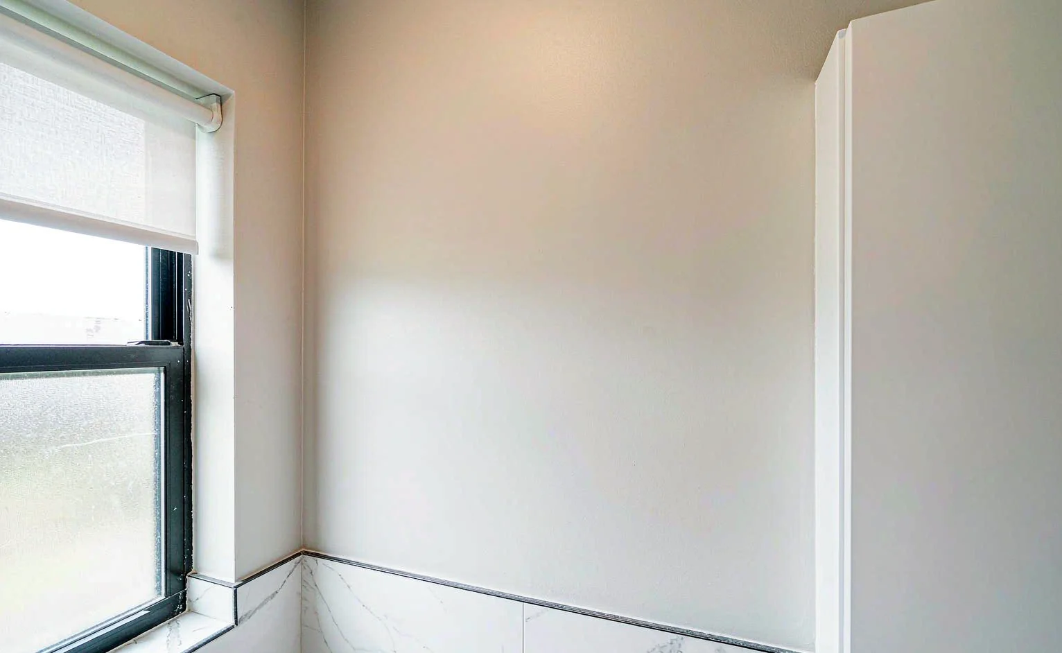 Bathroom wall finished with smooth washable anti-mould acrylic paint above marble-effect tiles