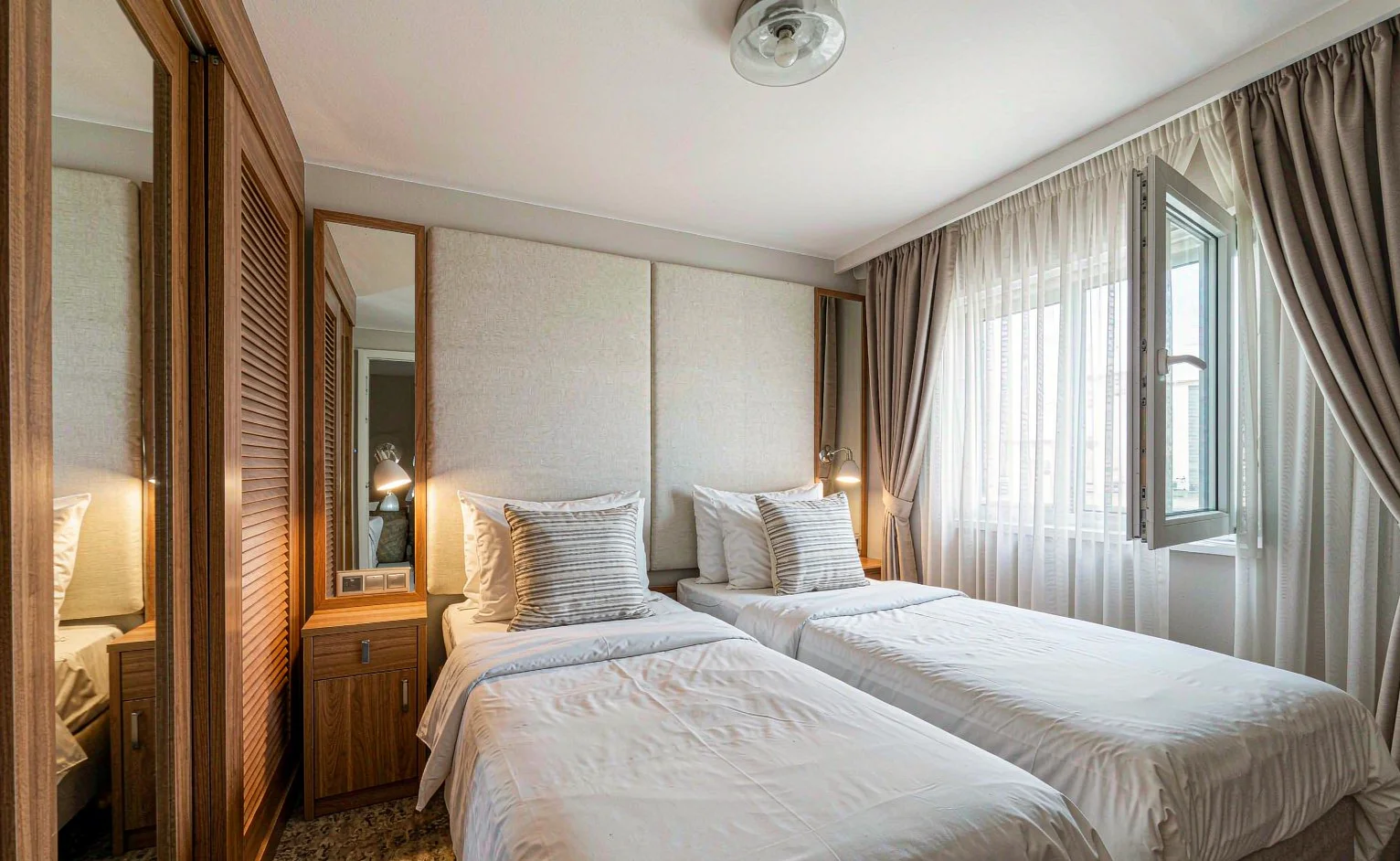 Hotel guest room with twin beds, upholstered headboard panels and built-in timber wardrobe supplied as a repeated keys package