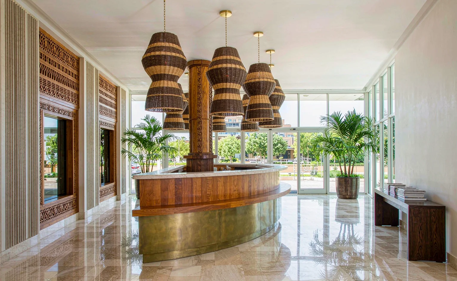 Hotel lobby reception with carved timber screens, brass counter and rattan pendant lights in an East African boutique hotel