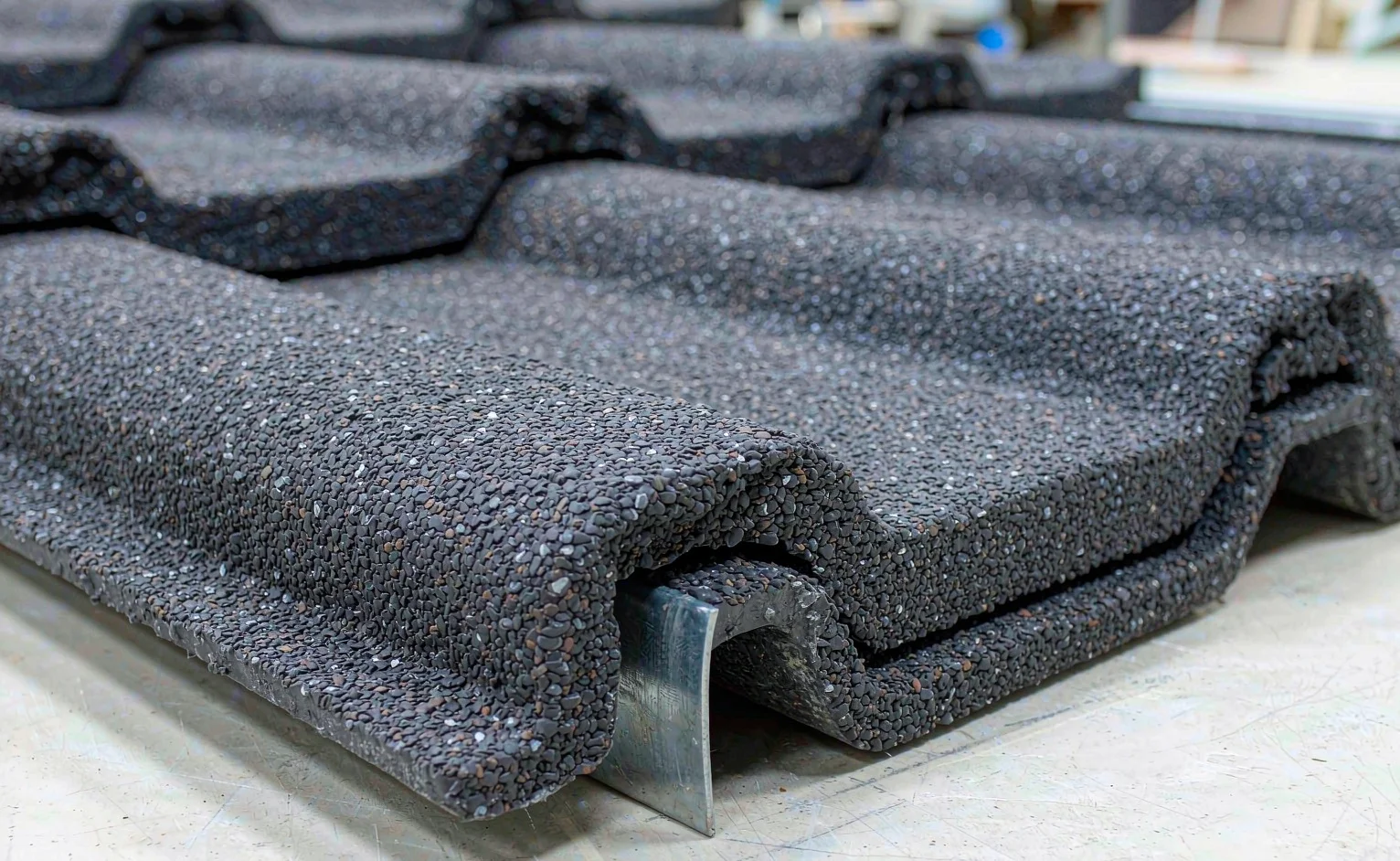 Close-up of interlocking stone-coated metal roof tile panels showing the acrylic-glazed stone chip surface over an aluzinc steel base
