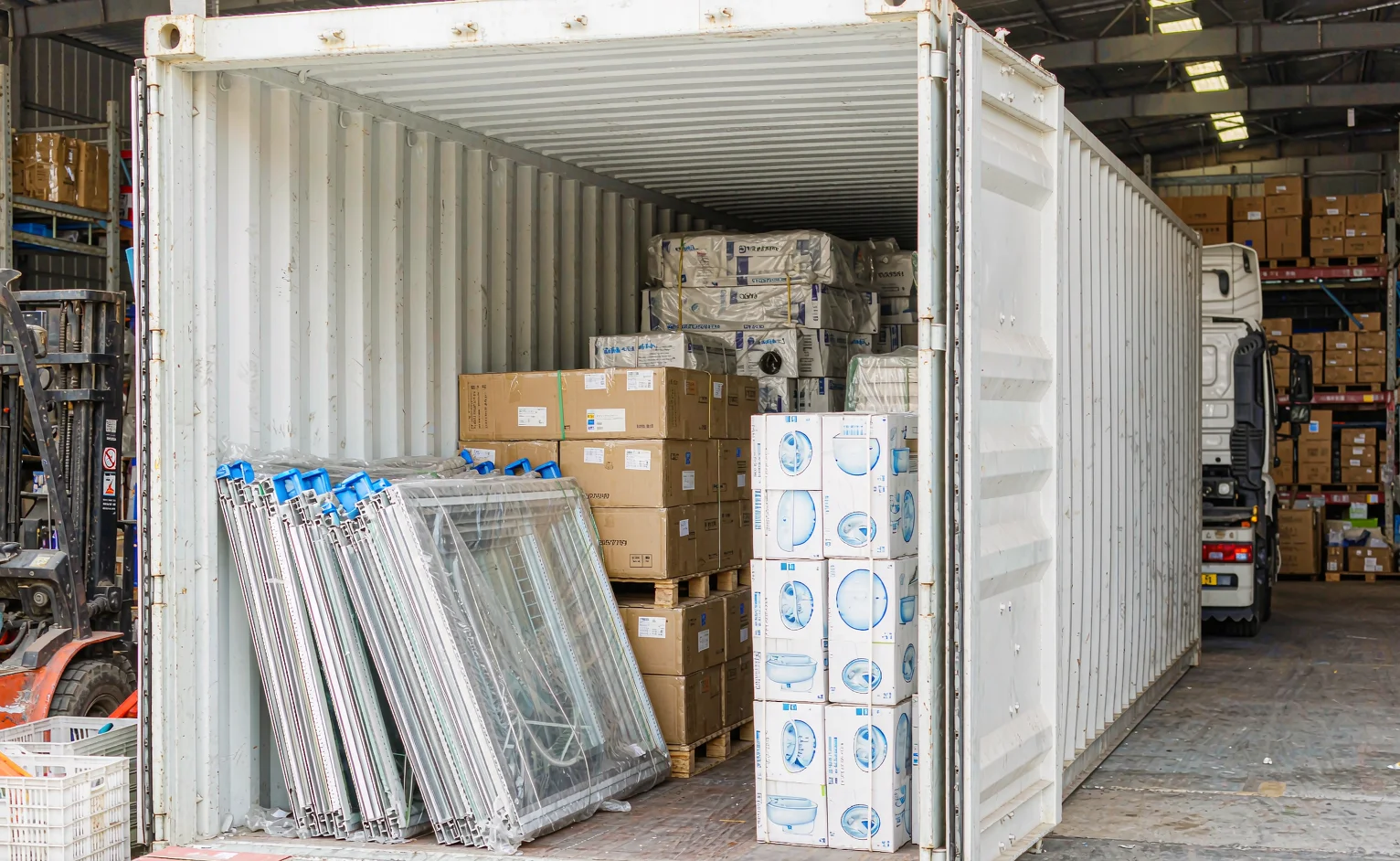 40ft shipping container being loaded with a whole-house building materials package: tile cartons, aluminium window frames and boxed sanitary ware
