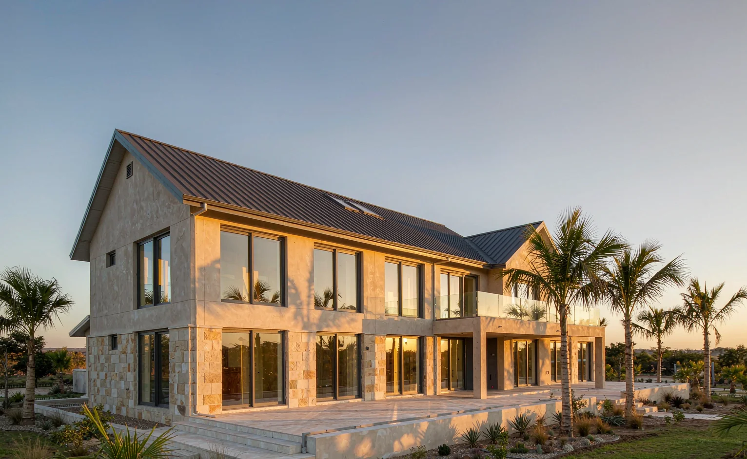 Completed two-storey East African villa delivered as a whole-house material package, with metal tile roof, aluminium windows and stone-clad base