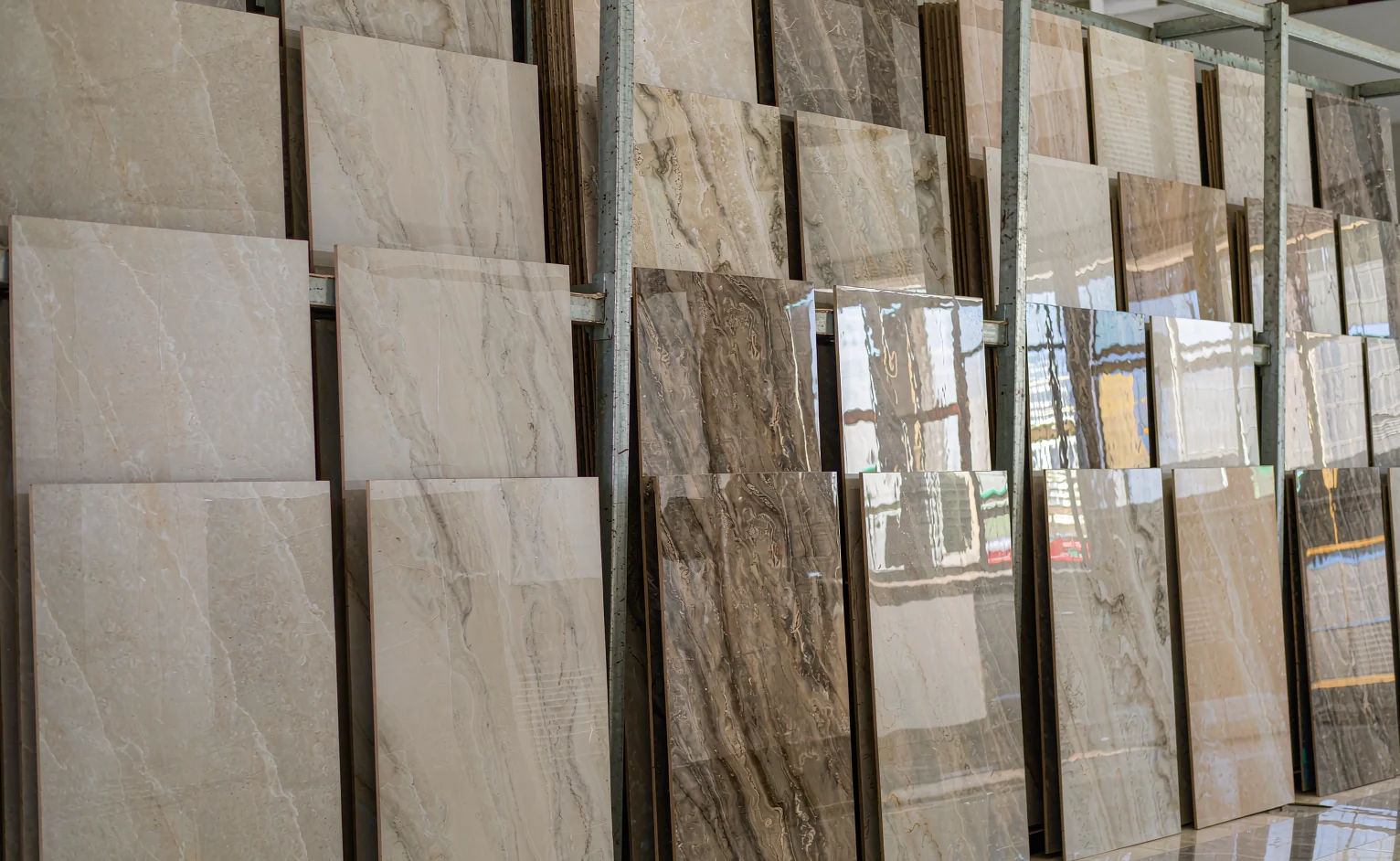 Showroom rack of large-format sintered stone slabs in matte and polished grey, beige and cream finishes