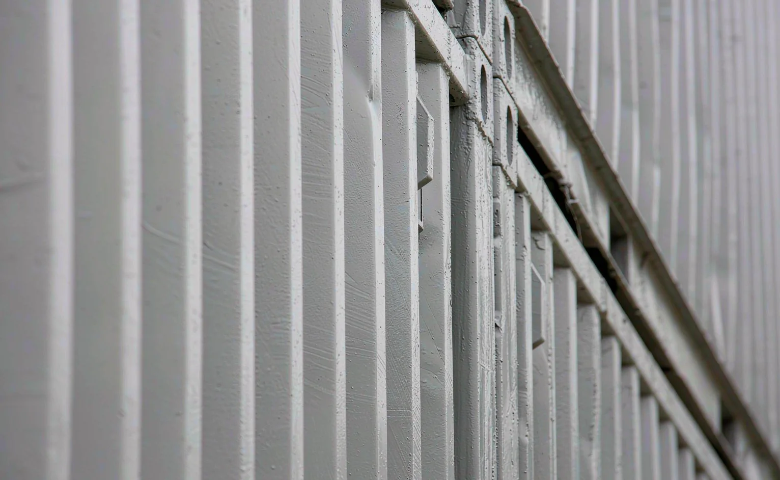 Close-up of a corrugated shipping container steel wall with corner castings under a fresh anti-corrosion coating