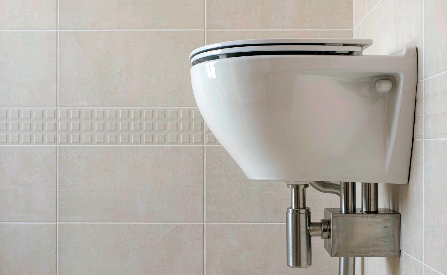 Wall-hung vitreous china WC with concealed cistern in a tiled bathroom