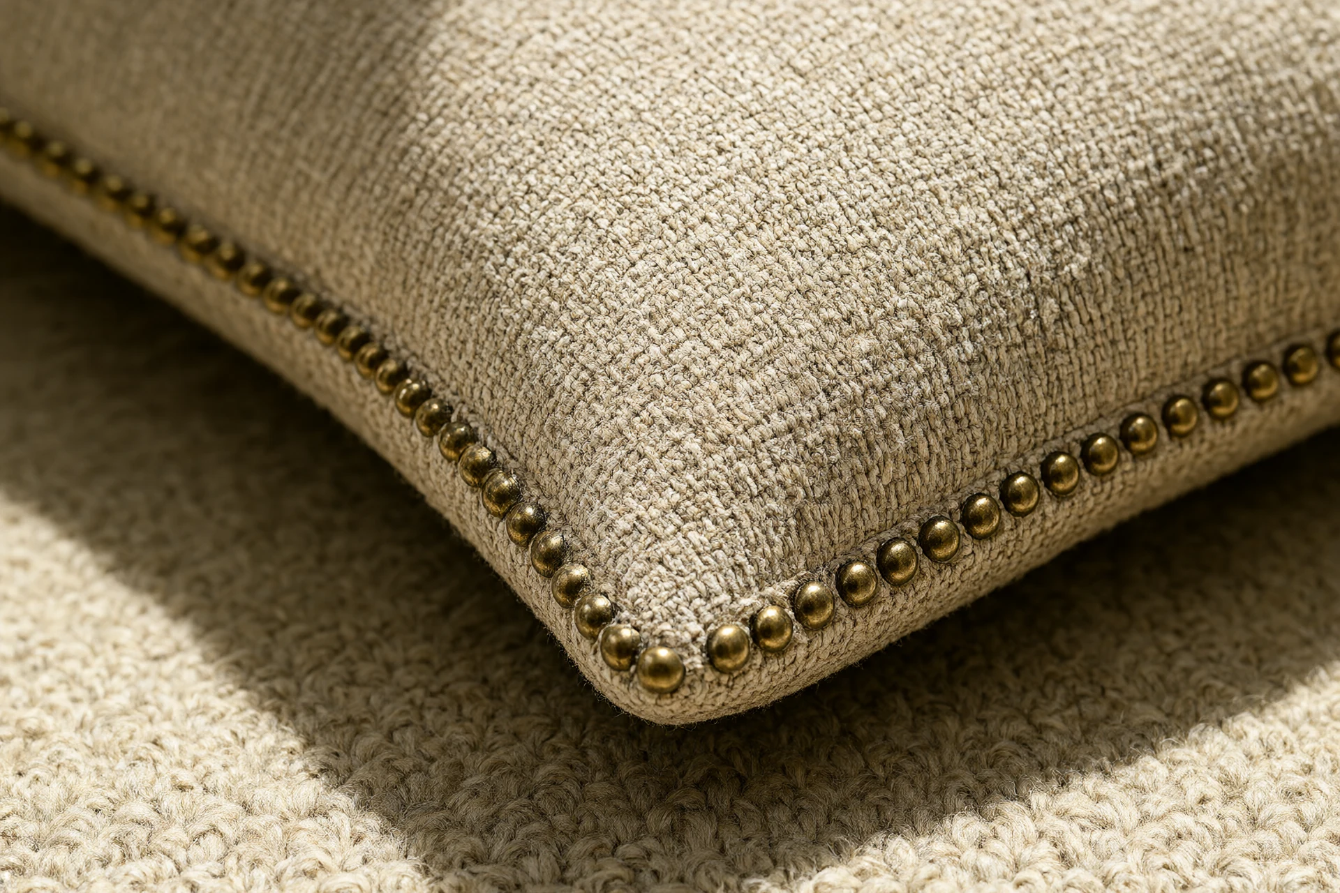 Macro detail of upholstery fabric weave with brushed brass stud trim and wool rug pile