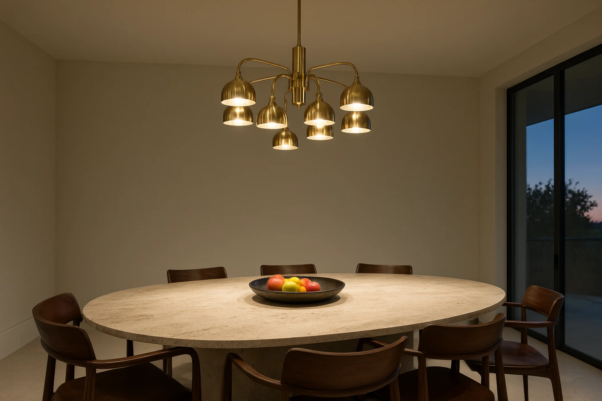 Dining room at dusk with brass pendant cluster above travertine table and hidden cove lighting
