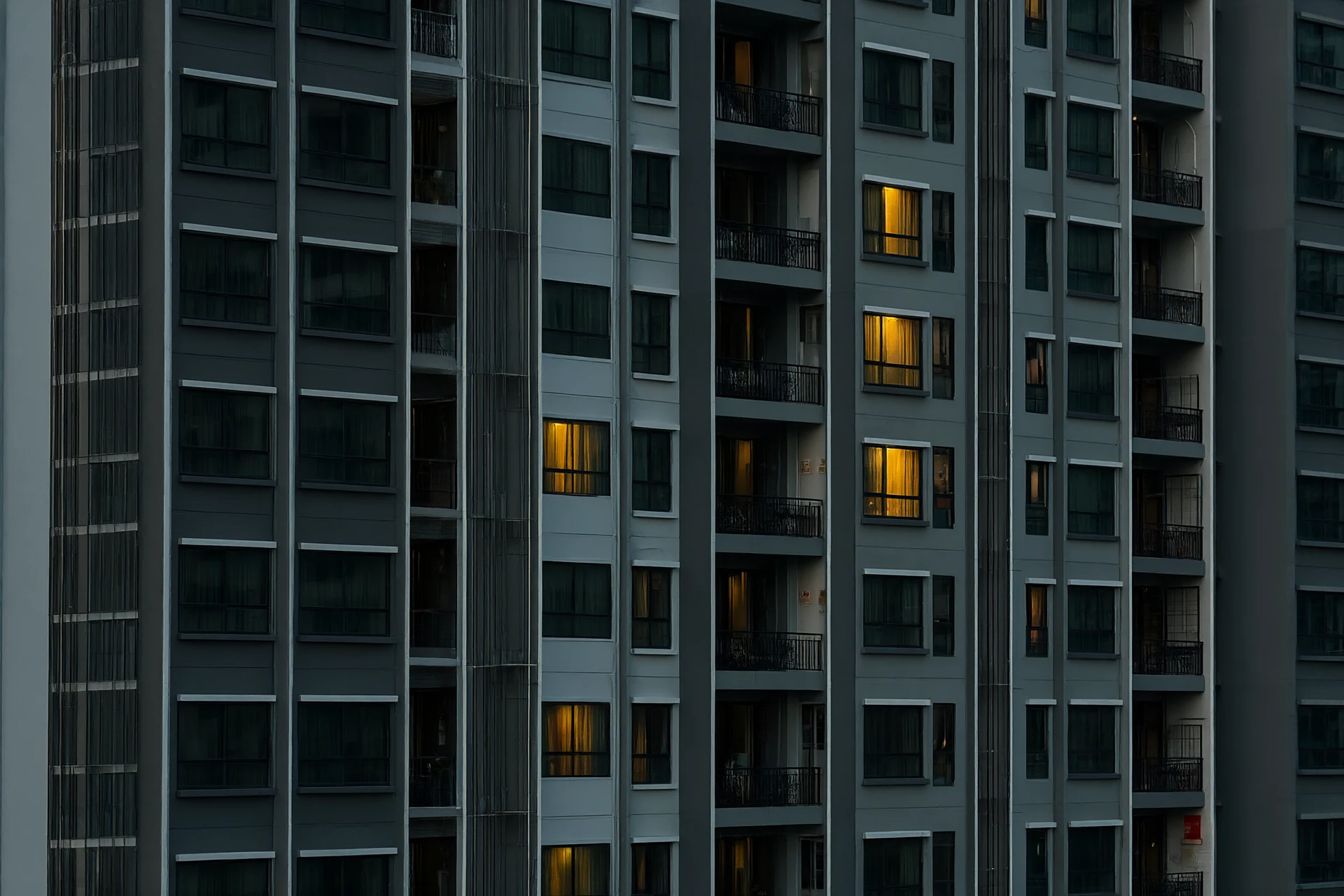 Modern mixed-use tower in Thailand at twilight with warm interior glow and subtle fire-safety signage