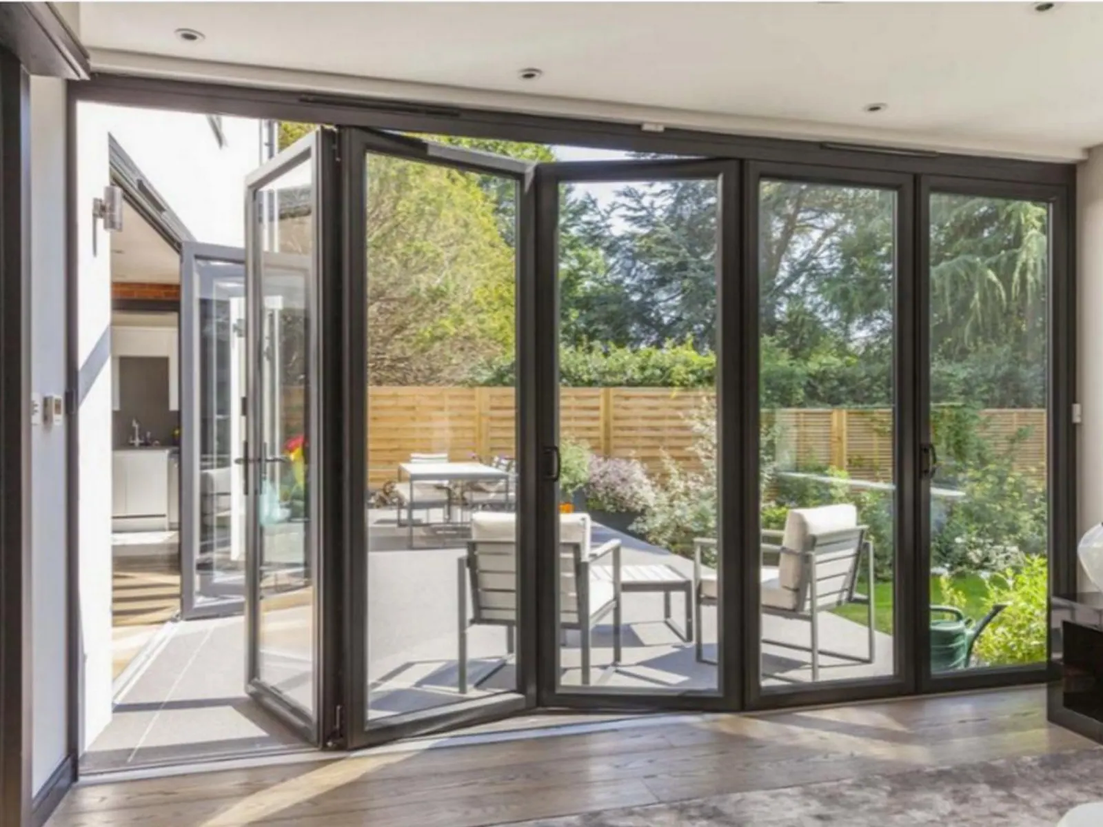 Aluminium bifold doors opening a villa living room to a garden — the whole-house opening package we specify in Juba